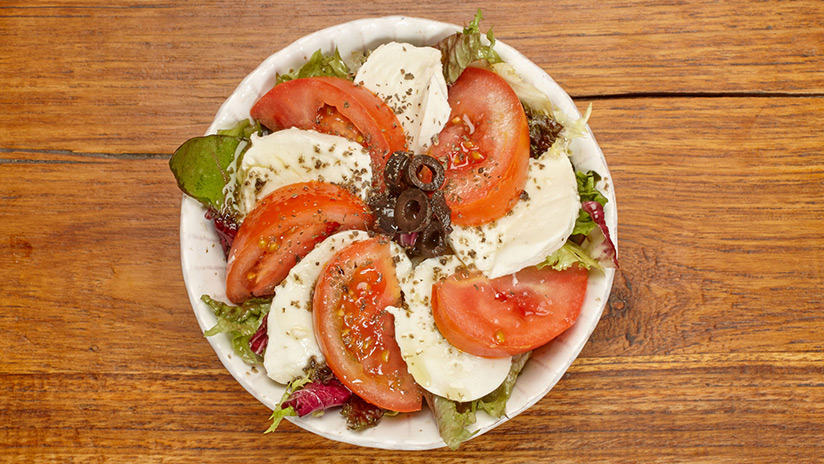 Ensalada caprese: Mezclum de lechugas, mozzarella, tomate, albahaca, olivas y salsa tapenade.