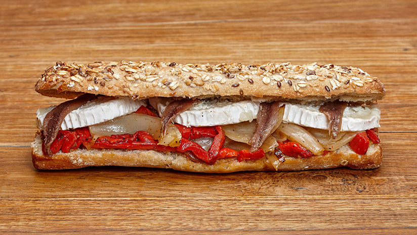 Bocadillo de queso de cabra con parrillada de verduras y anchoas y Pan de semilla.