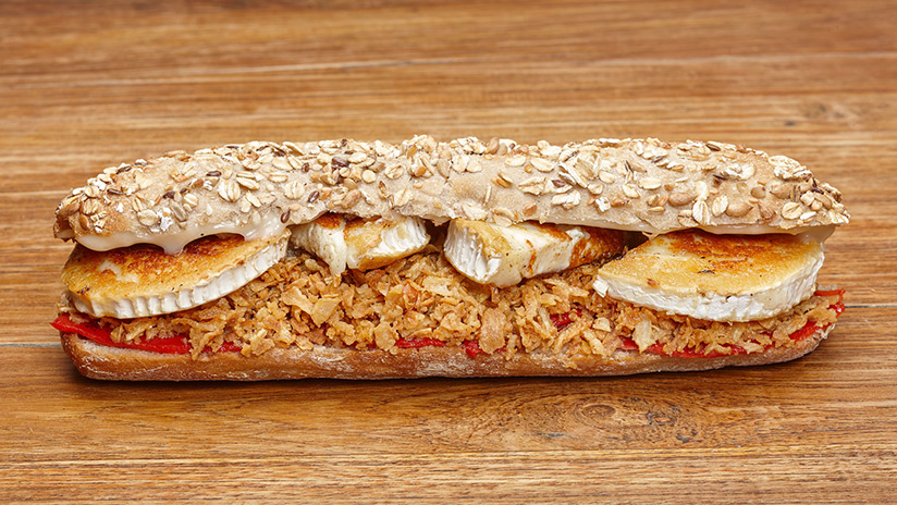 Bocadillo de rulo de cabra, pimiento, cebolla crujiente, mayonesa miel y Pan de semilla.