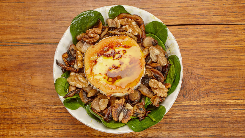 Ensalada de espinacas con: Rulo de cabra, champiñones, nueces y aliño dulce de mostaza.