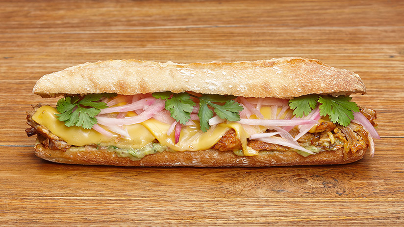 Bocadillo de Cochinita Pibil, cebolla roja, cilantro, queso fundido y guacamole.