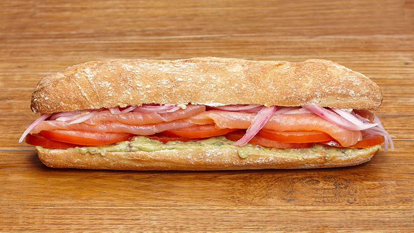 Bocadillo de salmón ahumado con guacamole, cebolla curtida, tomate y cremette de cebollino.